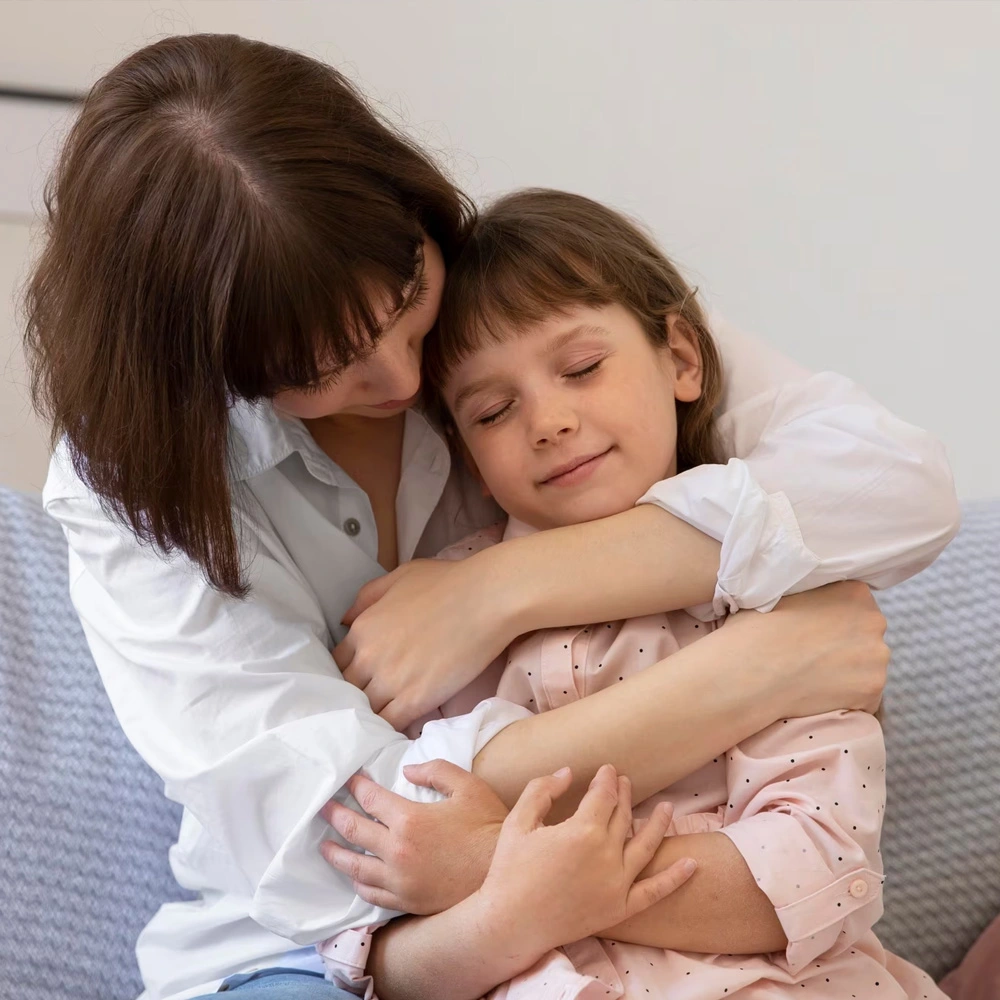 Mujer adulta abraza a una niña en señal de cariño y cuidado